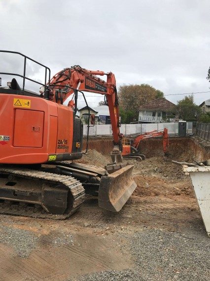 Two large orange excavators scooping dirt